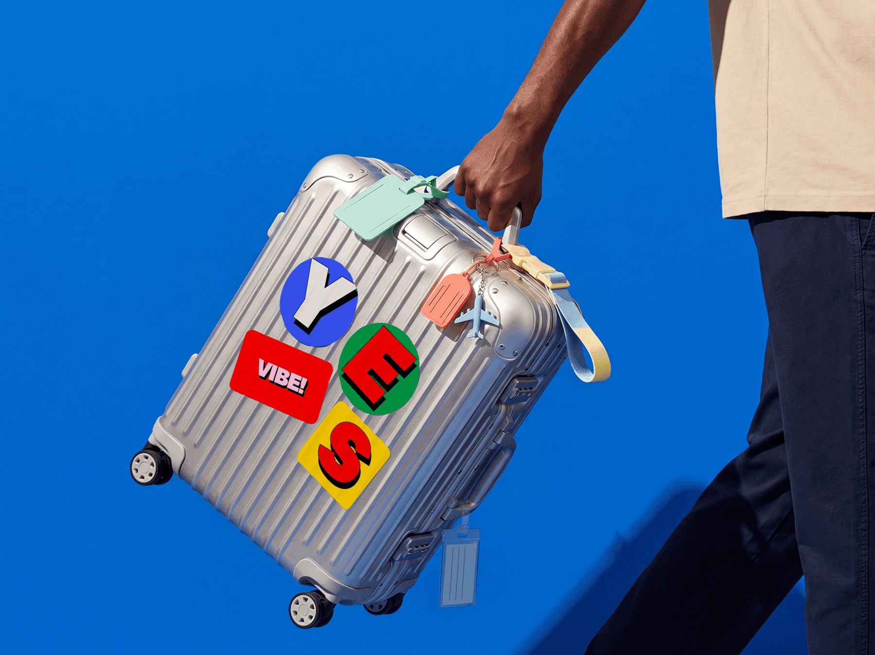 Traveler holding a refined suitcase covered with colorful printed travel stickers in a lifestyle scene