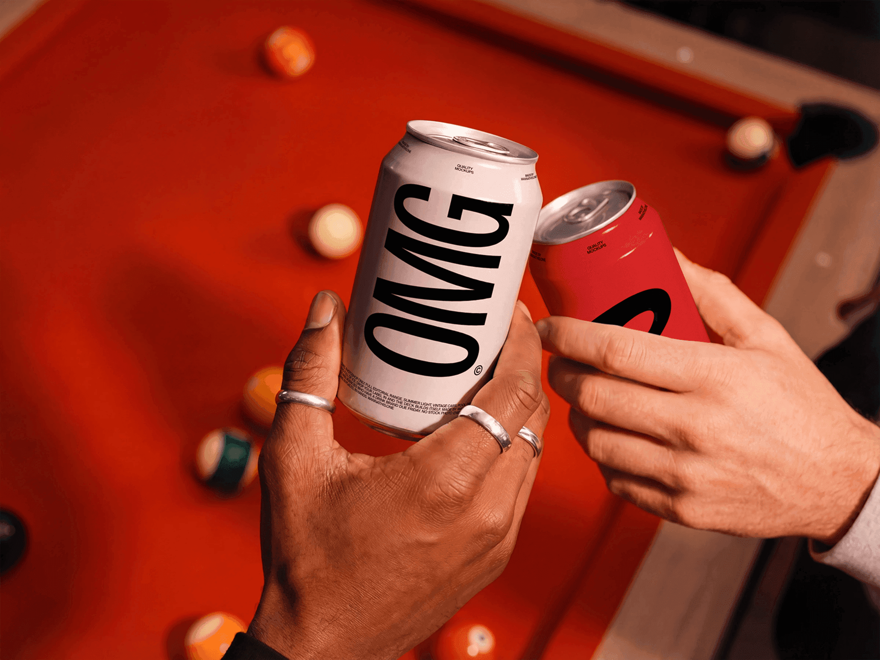 Two hands holding beverage can mockups near a pool table