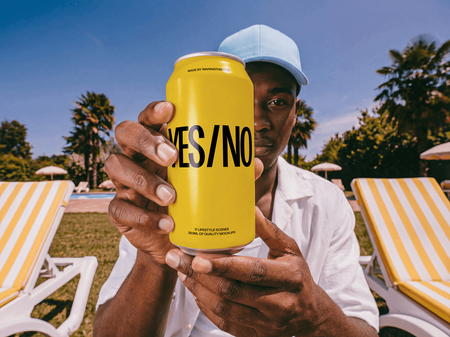Person holding a beverage can mockup outdoors near pool chairs