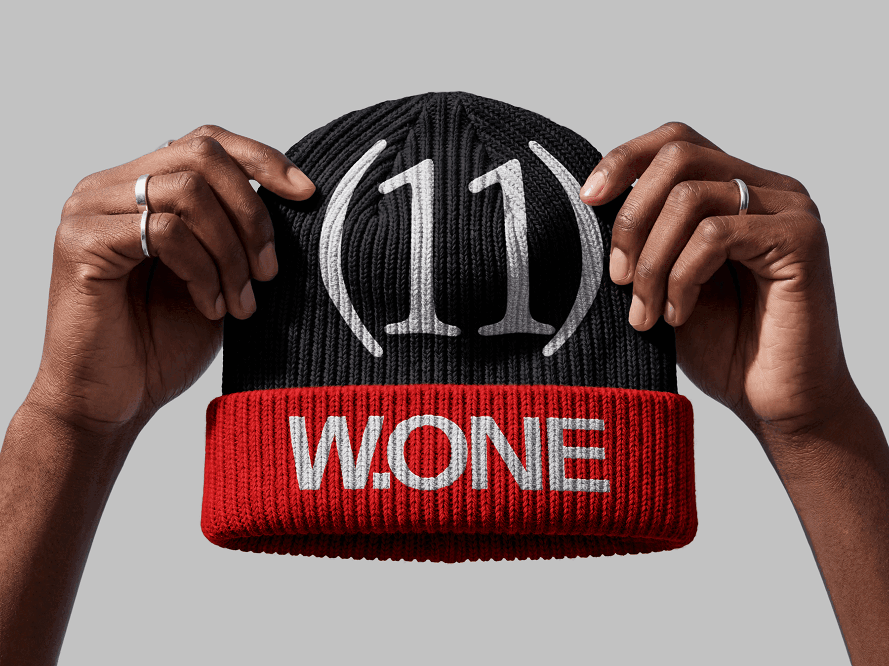 Hands holding a beanie hat in a studio setting