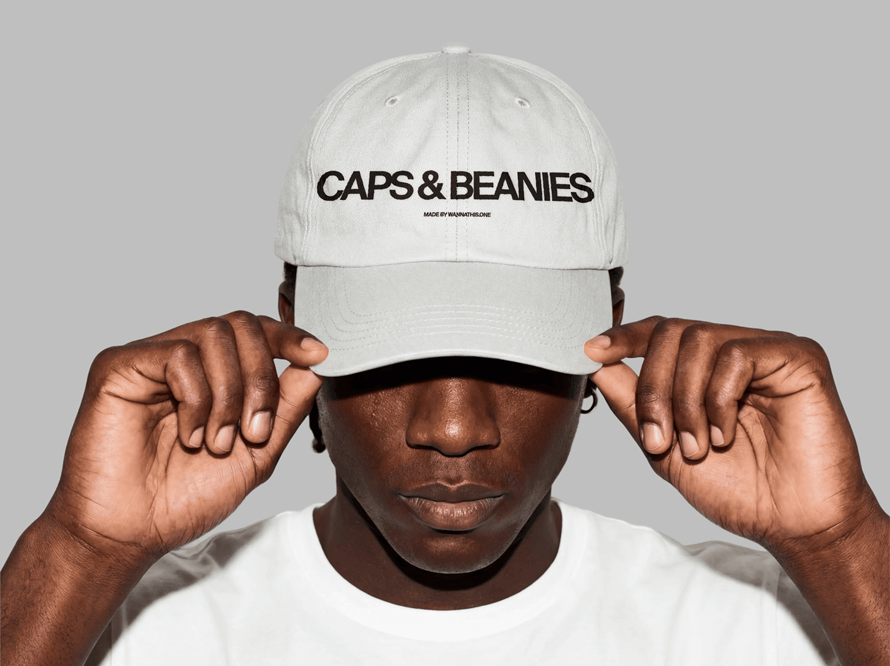 Model holding the brim of a baseball cap in a studio pose