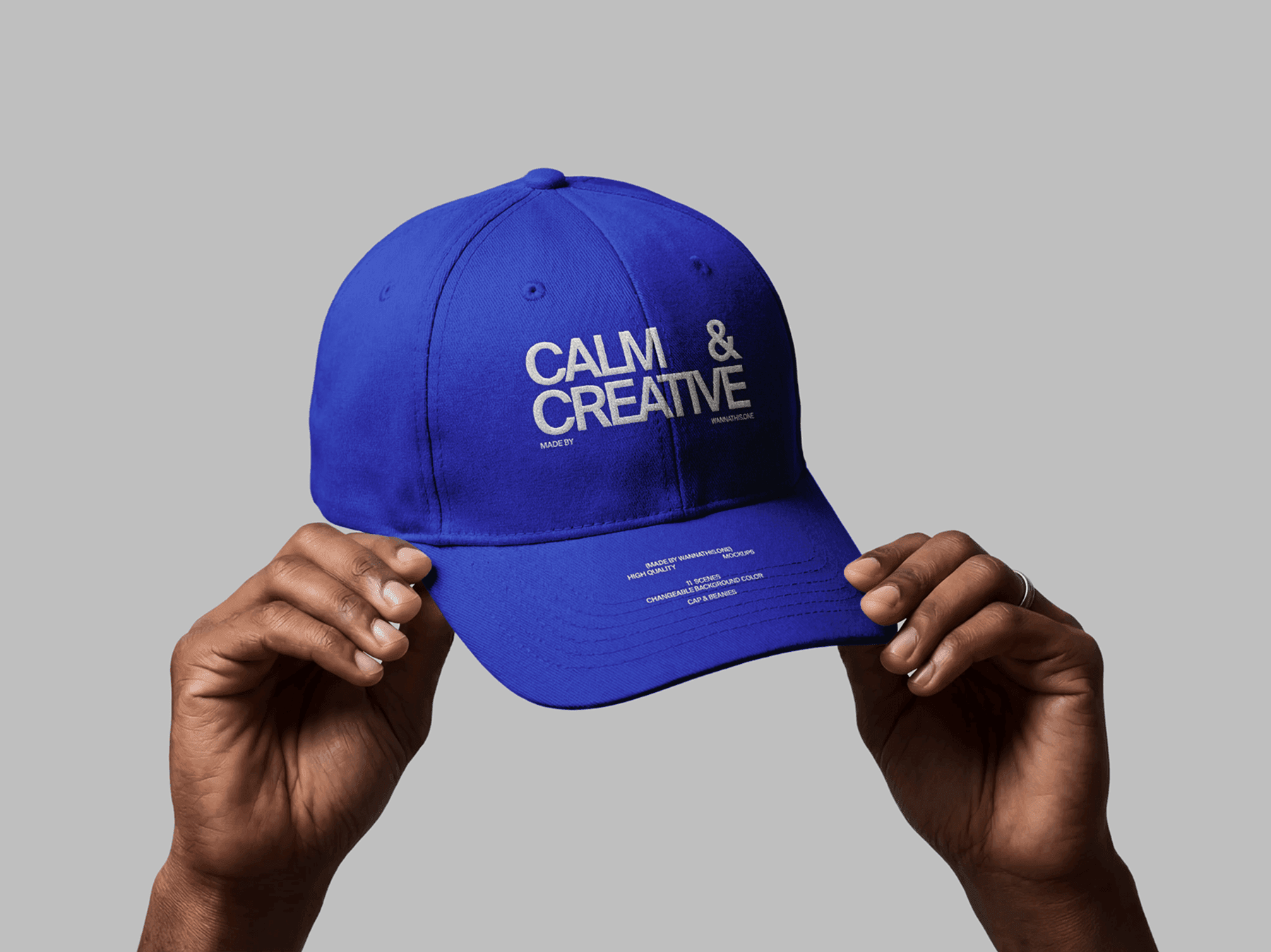 Hands holding a baseball cap in front of a neutral background