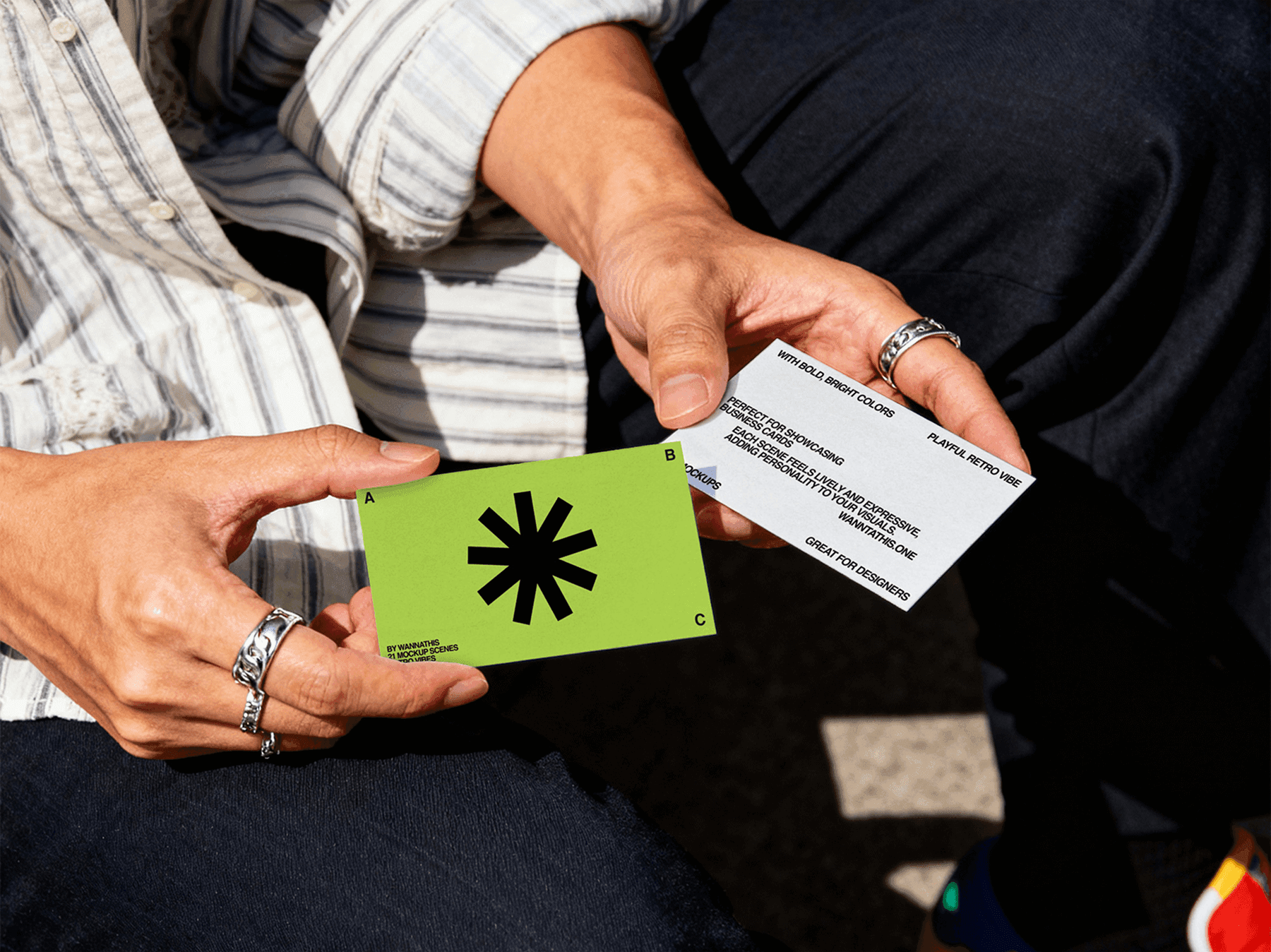 Two business card mockups held in hand outdoors under sunlight