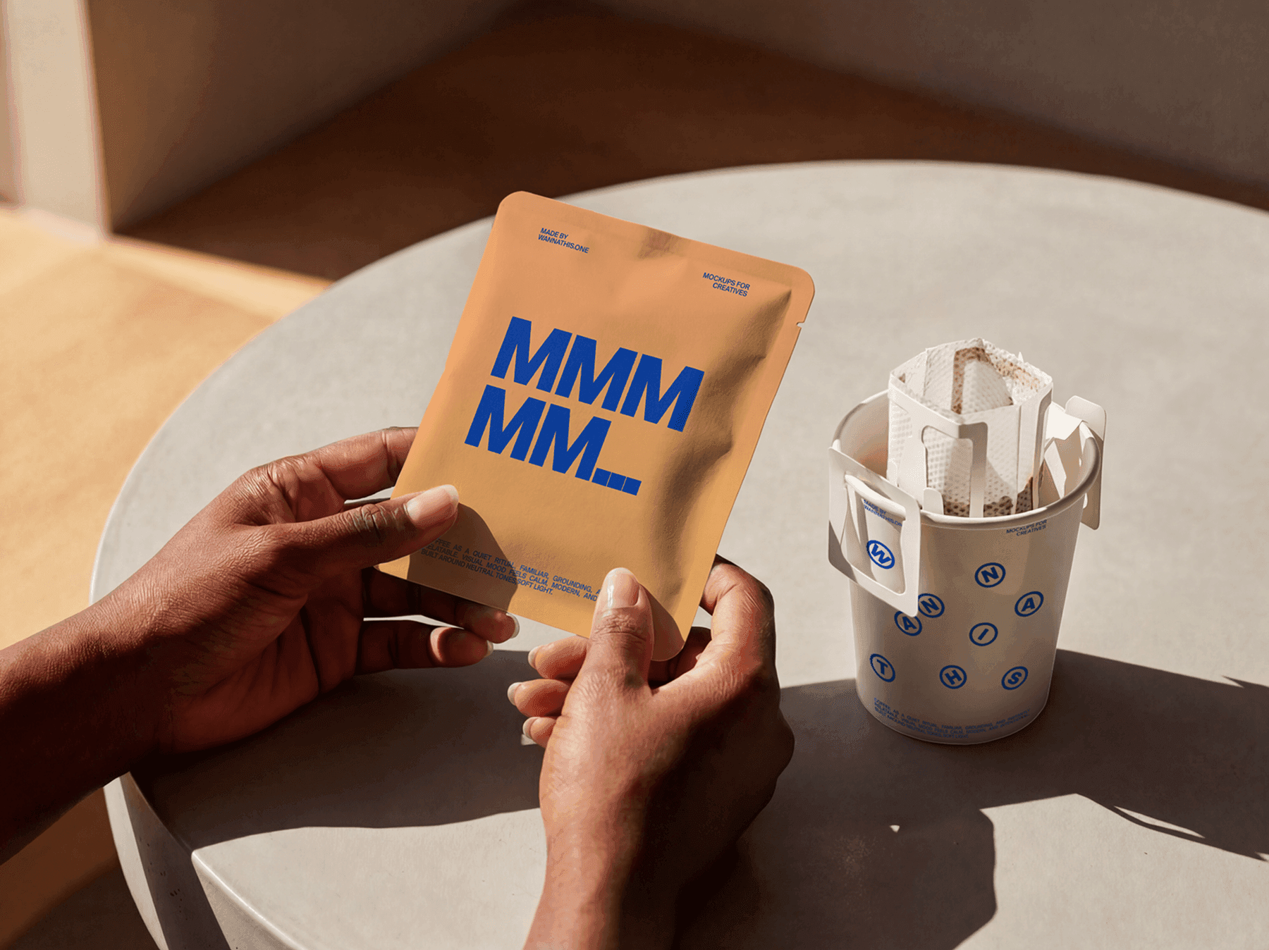 Hands holding a coffee sachet near a takeaway cup with drip filter