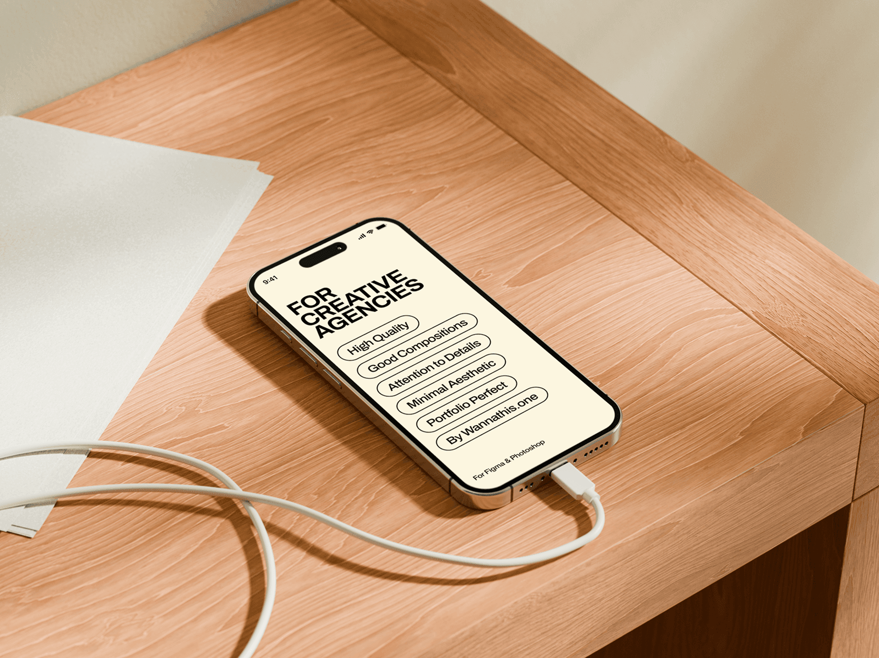 iPhone mockup placed on the corner of a wooden desk with charging cable