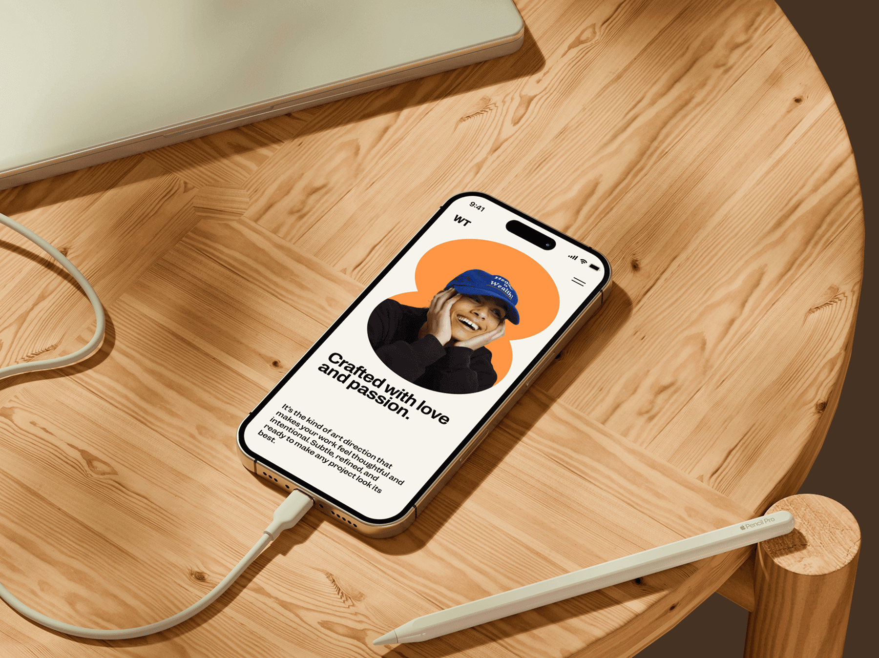 iPhone mockup placed on a wooden desk next to a laptop and pencil