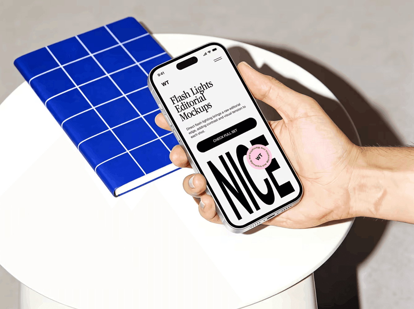 Editorial iPhone mockup with flash-photography styling, shown next to a blue grid notebook — a scene for presenting a brand identity across digital touchpoints