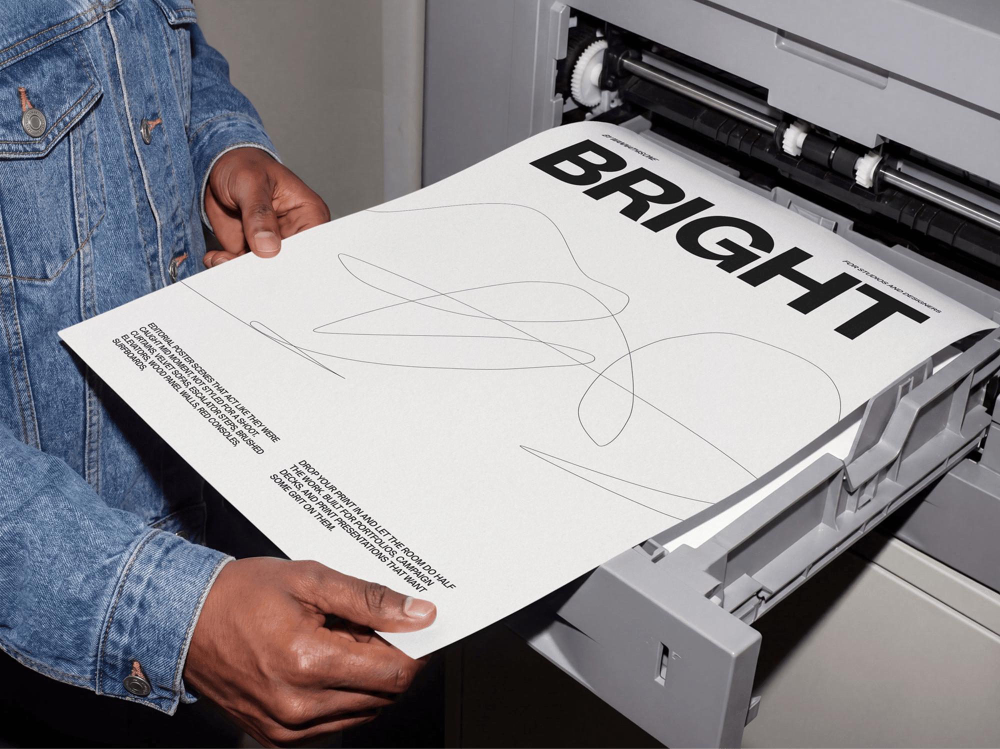 Person holding a freshly printed editorial poster mockup near a refined print press machine in studio scene
