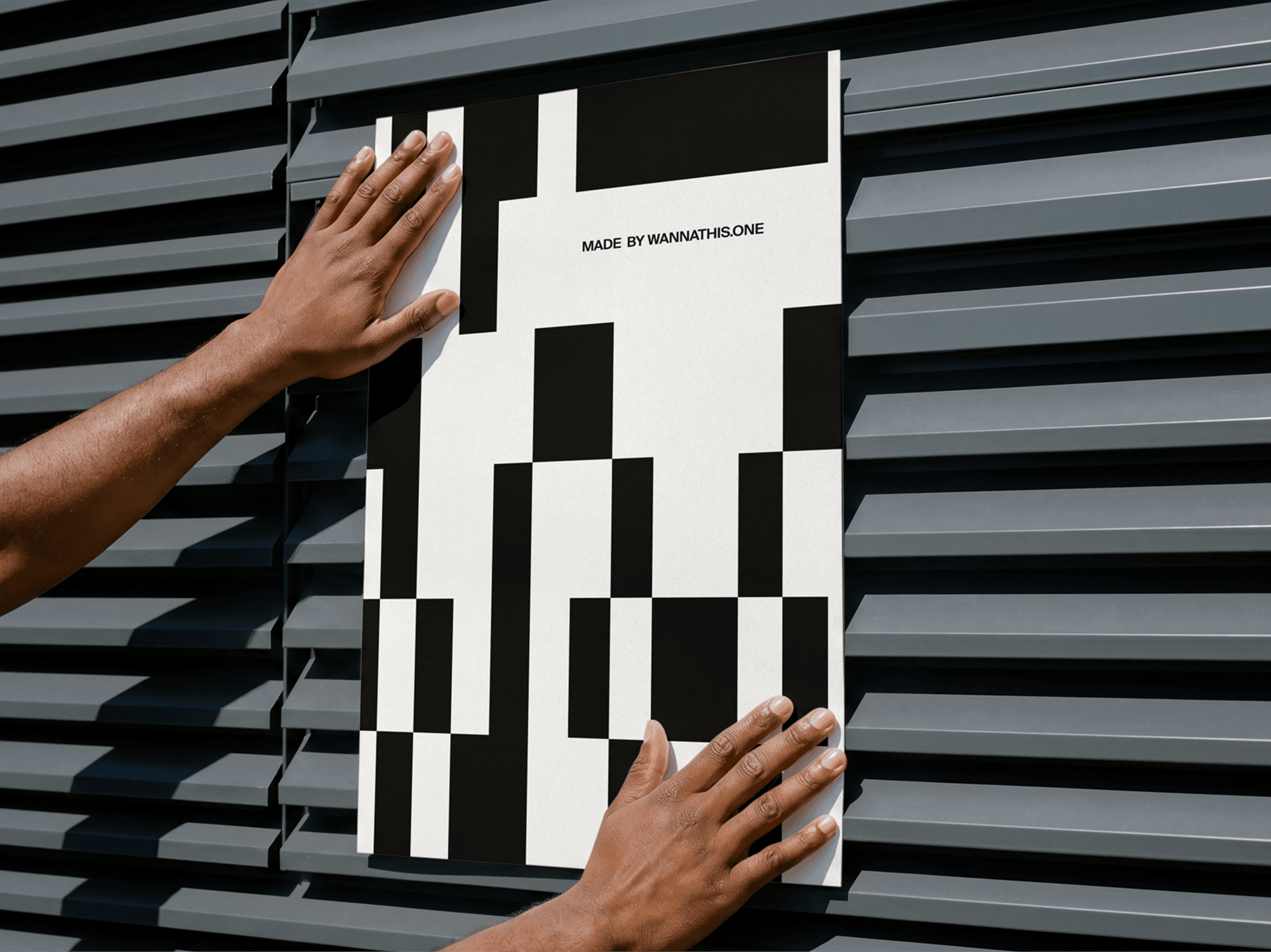 Hands placing an editorial poster mockup on a sleek refined metal wall surface in a bold modern studio scene