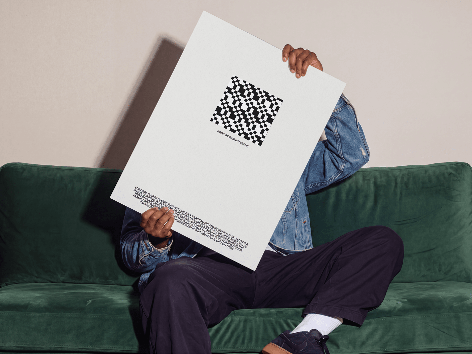 Person sitting on a soft sofa while holding a large editorial poster mockup in a refined cozy interior scene