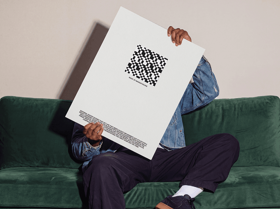 Person sitting on a soft sofa while holding a large editorial poster mockup in a refined cozy interior scene