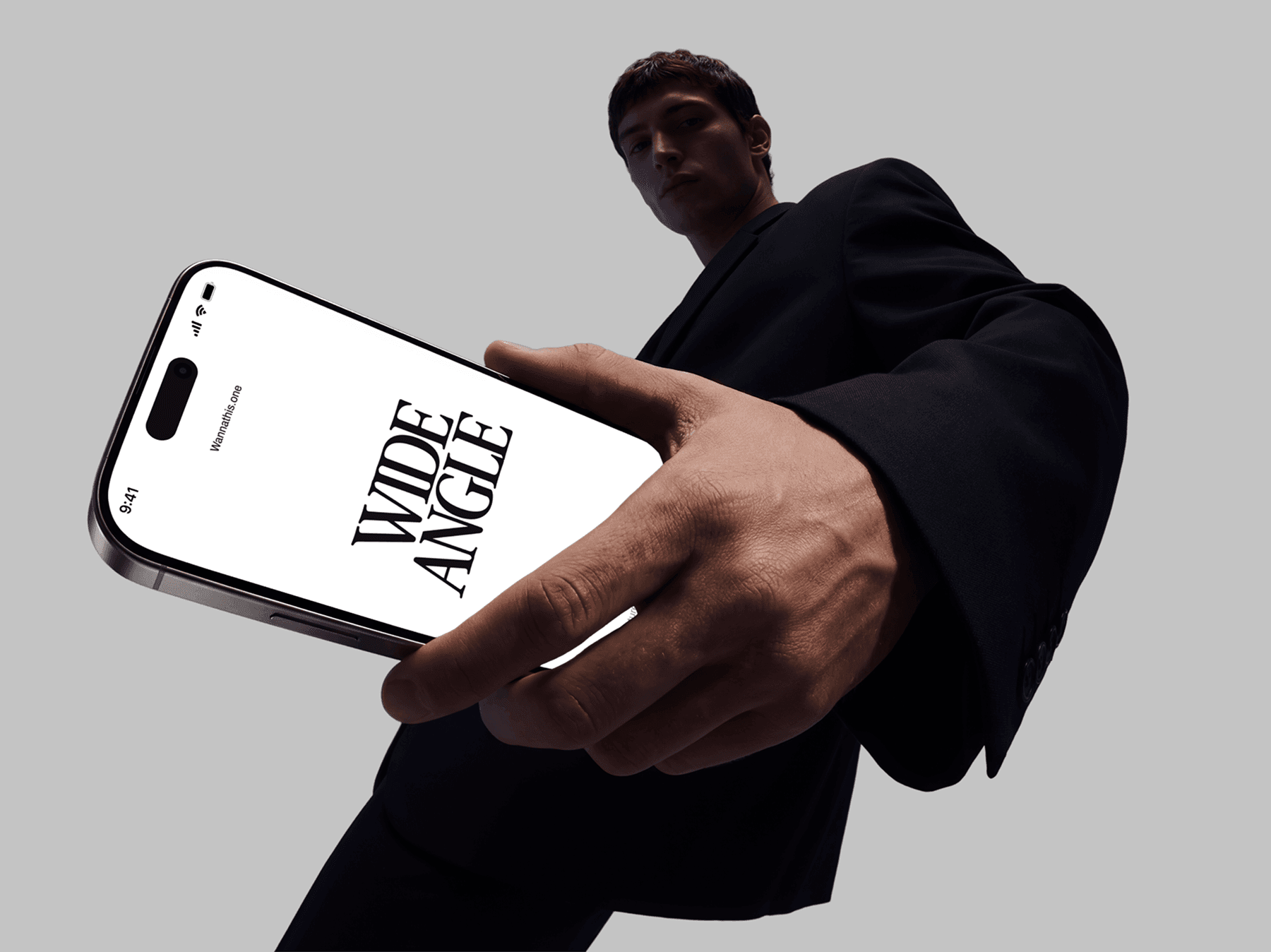 Person holding an iPhone mockup close to the camera in a fashion pose
