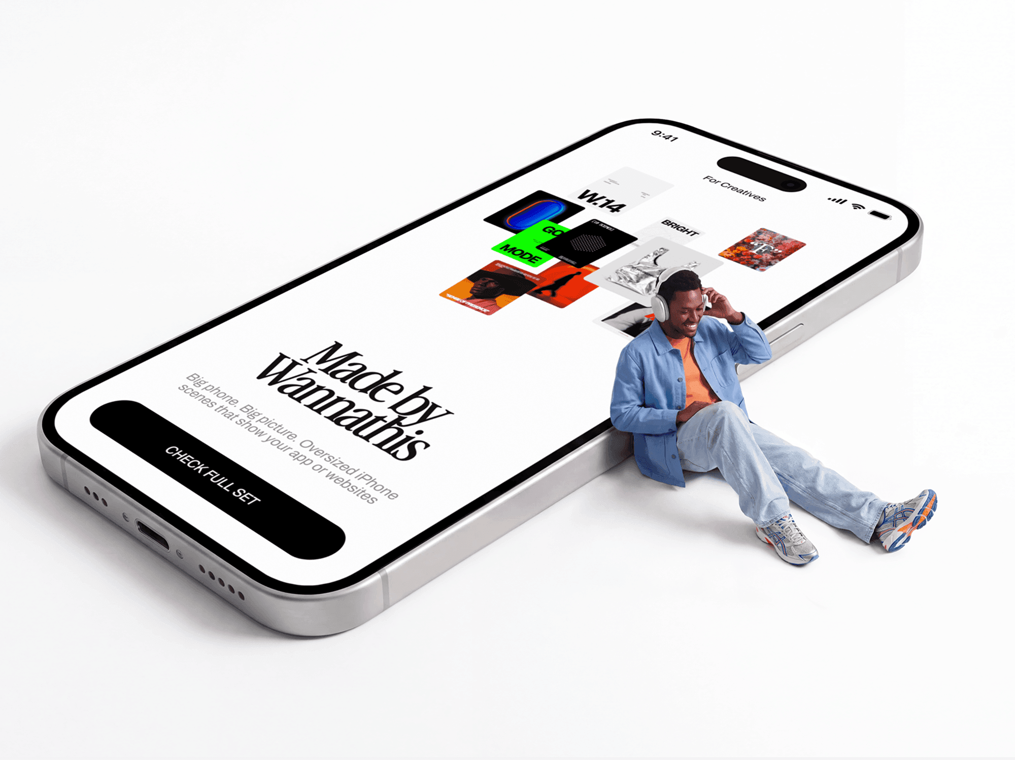Oversized iPhone tilted on the ground with a person sitting on the floor beside it