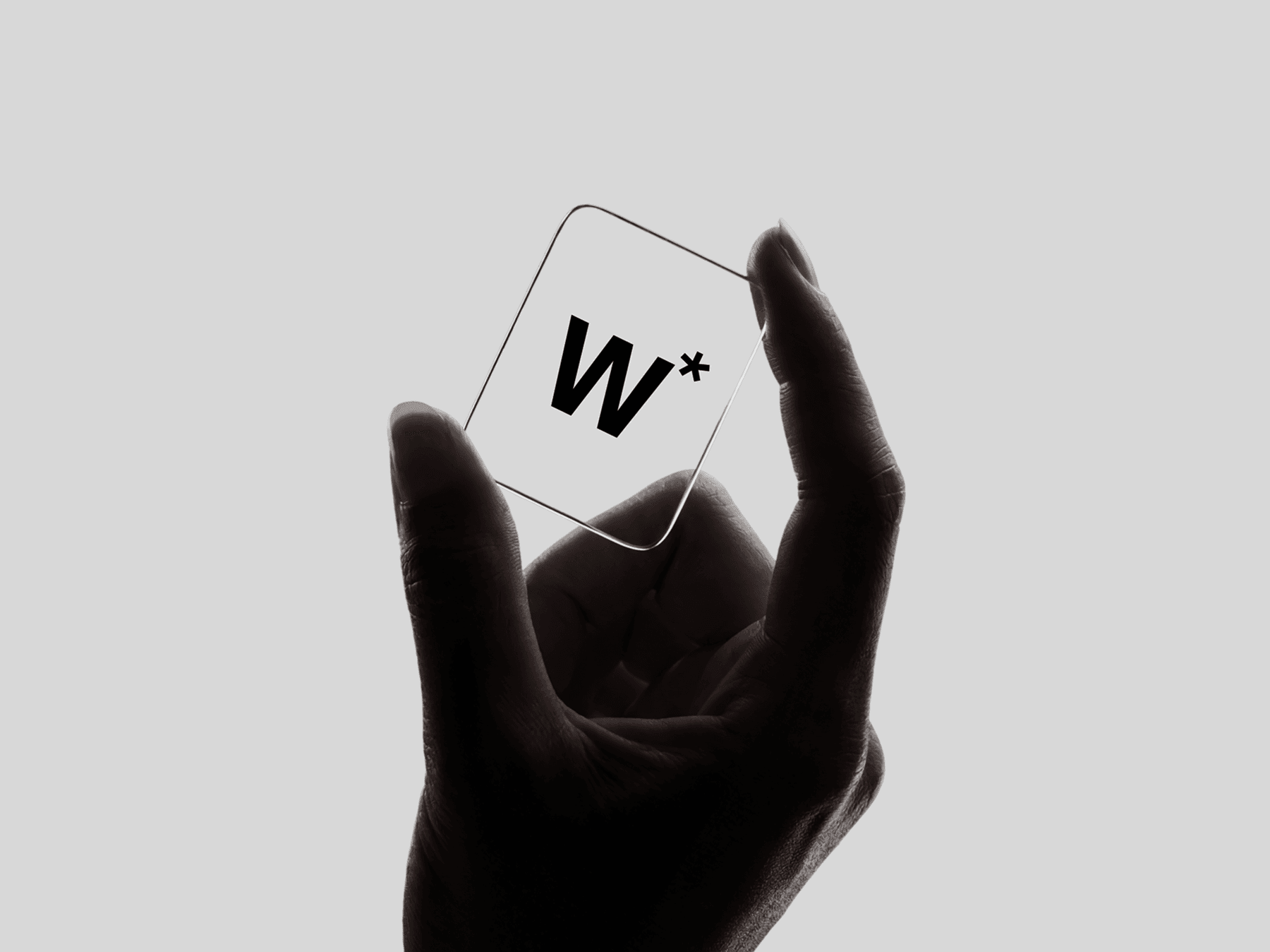 Hand holding a transparent glass card with a soft pinch grip in a clean setting