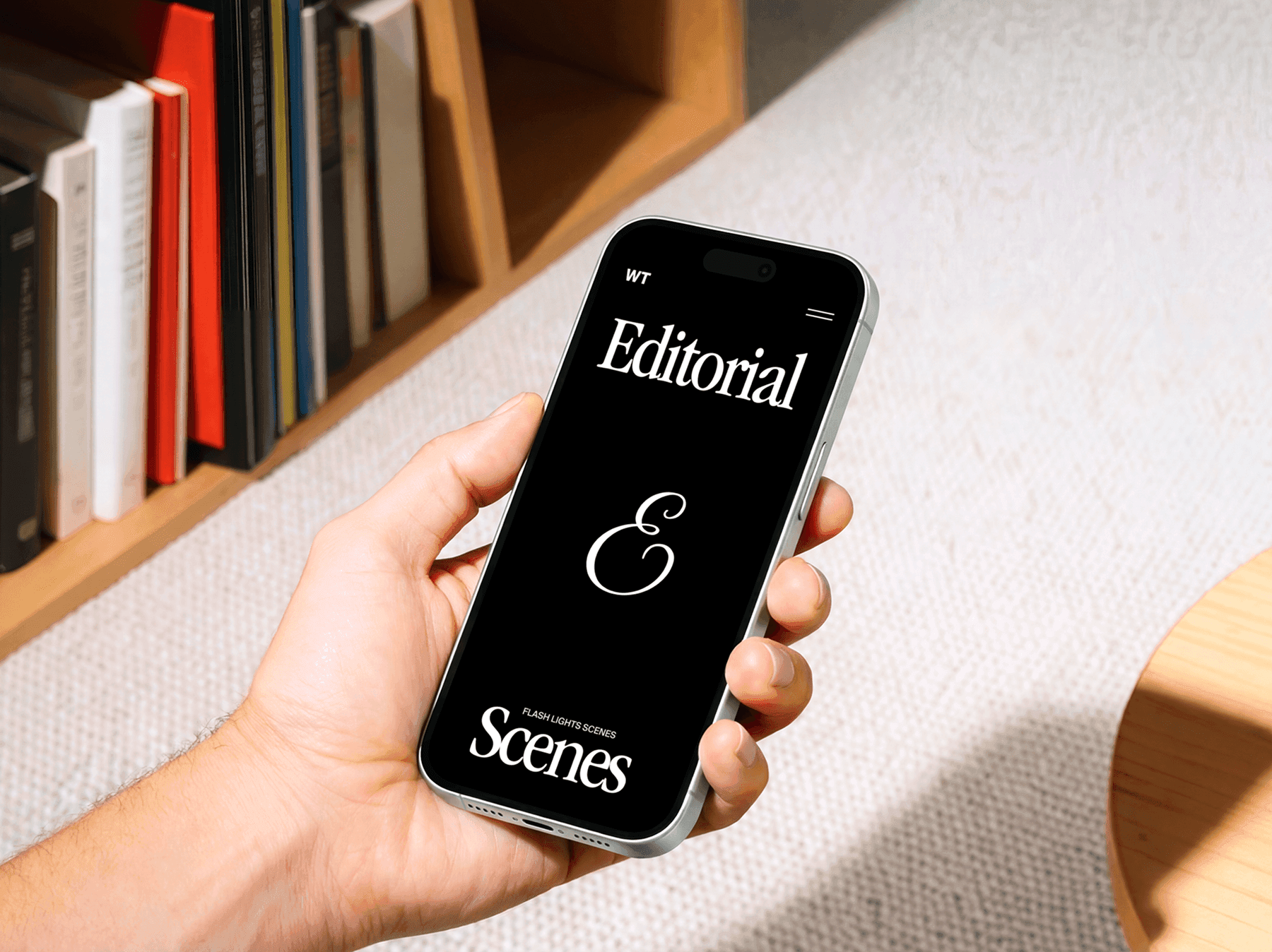 Hand holding an iPhone near a bookshelf in a modern interior