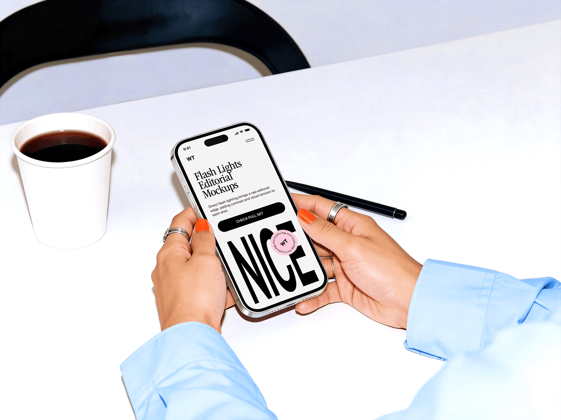 Hands holding an iPhone above a clean desk with everyday objects nearby
