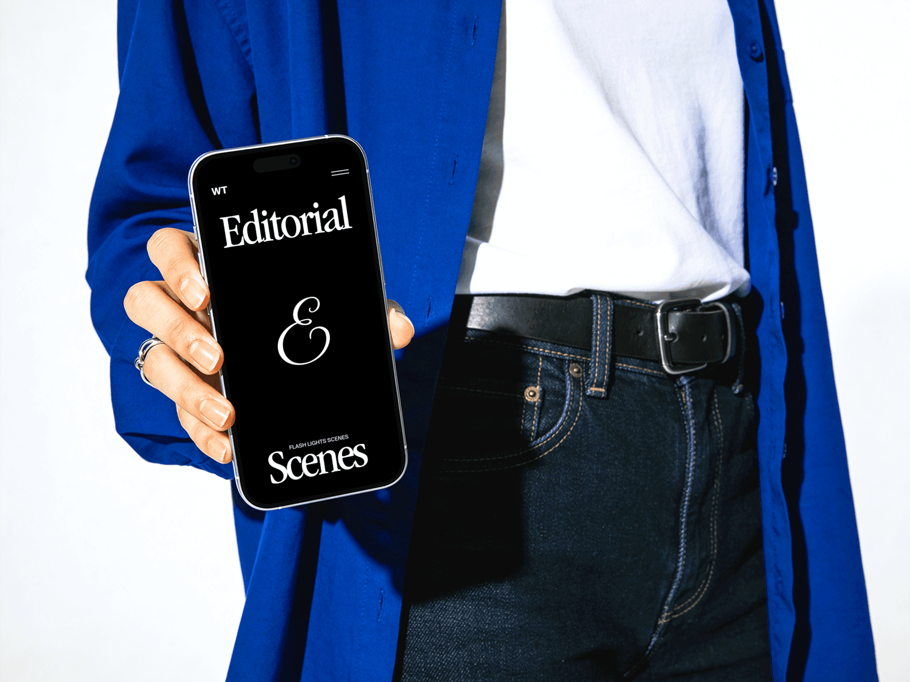 Person standing while holding an iPhone in a modern editorial setting