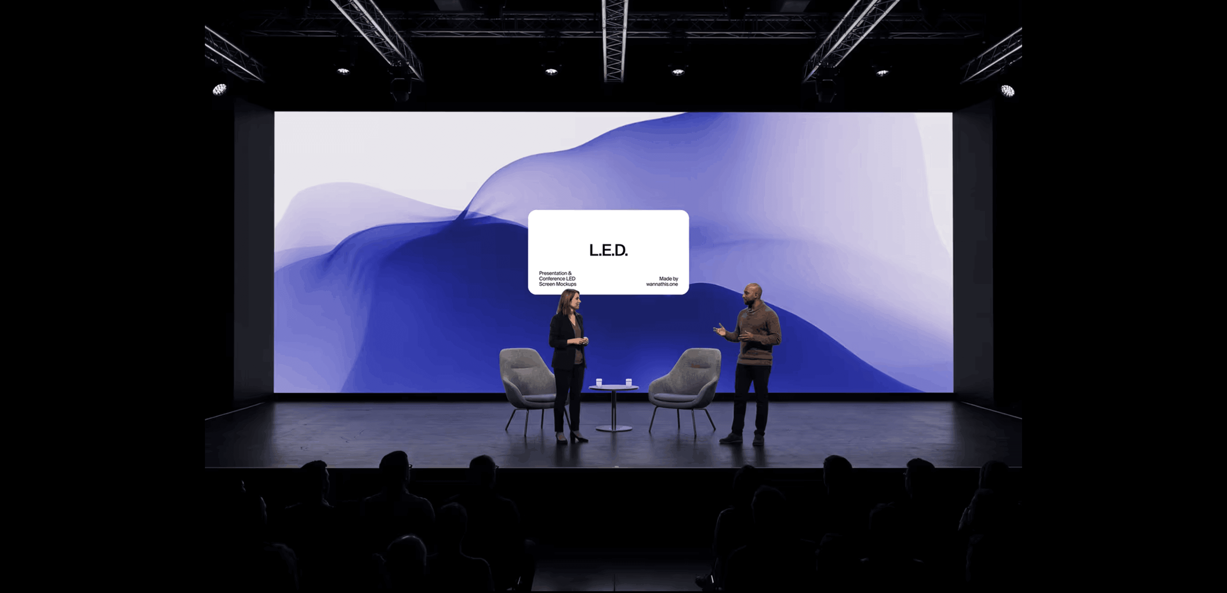 Two speakers on stage in front of a large LED screen mockup with a blue wave design - a presentation scene for showing brand identity at environmental scale.