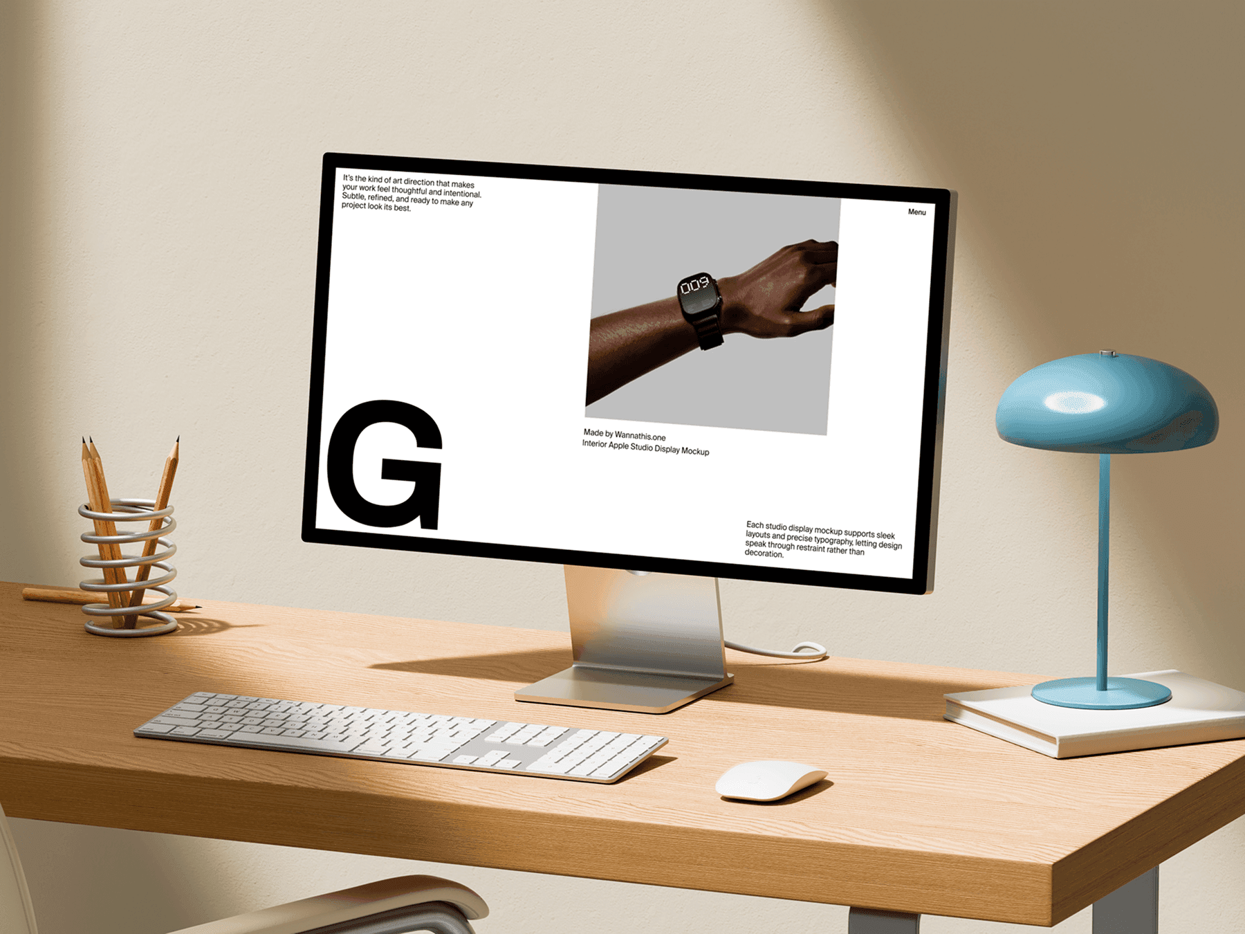 Studio display monitor placed on a clean wooden desk with keyboard and lamp