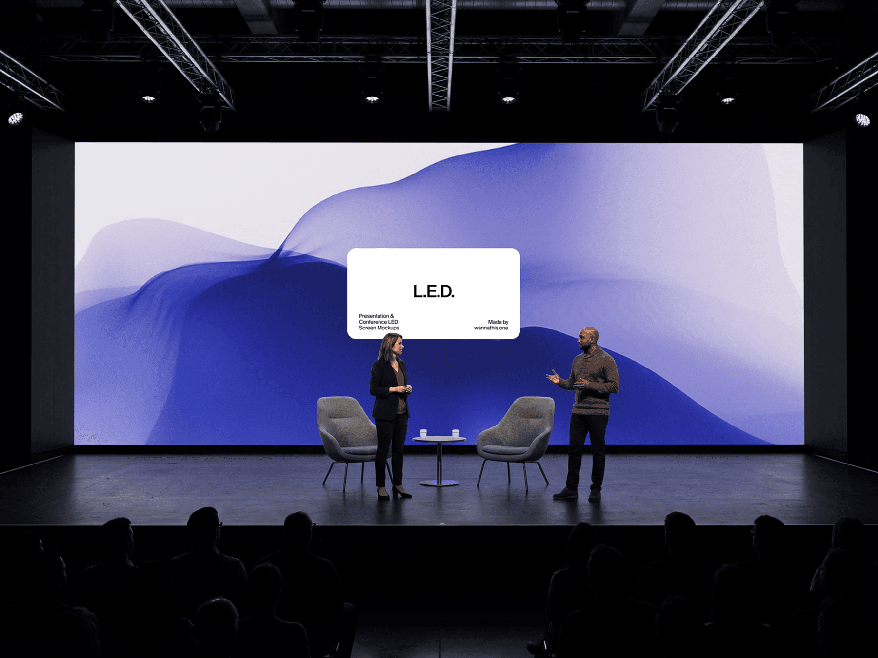 Two speakers presenting on stage in front of a large LED display screen