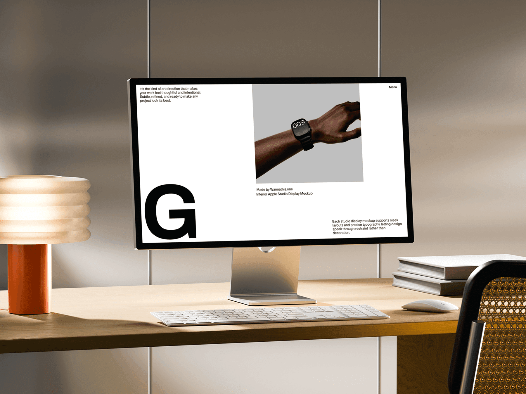 Studio display monitor on a desk with a table lamp and stacked books
