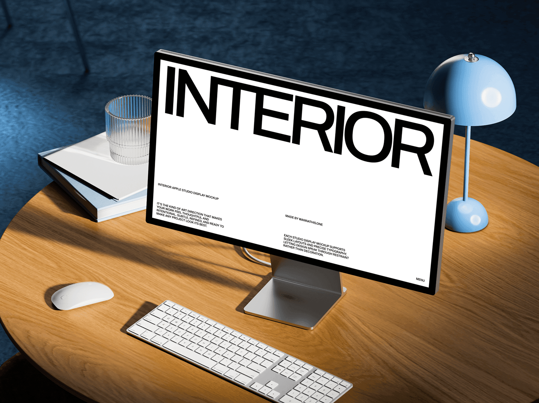 Studio display monitor placed on a wooden desk with keyboard and table lamp