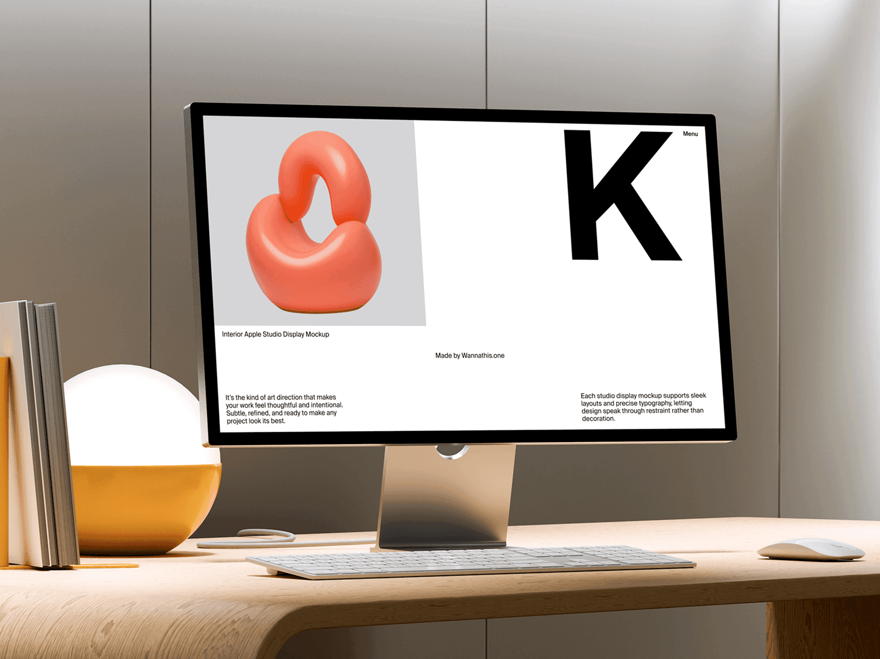 Studio display monitor on a desk with stacked books and a decorative lamp