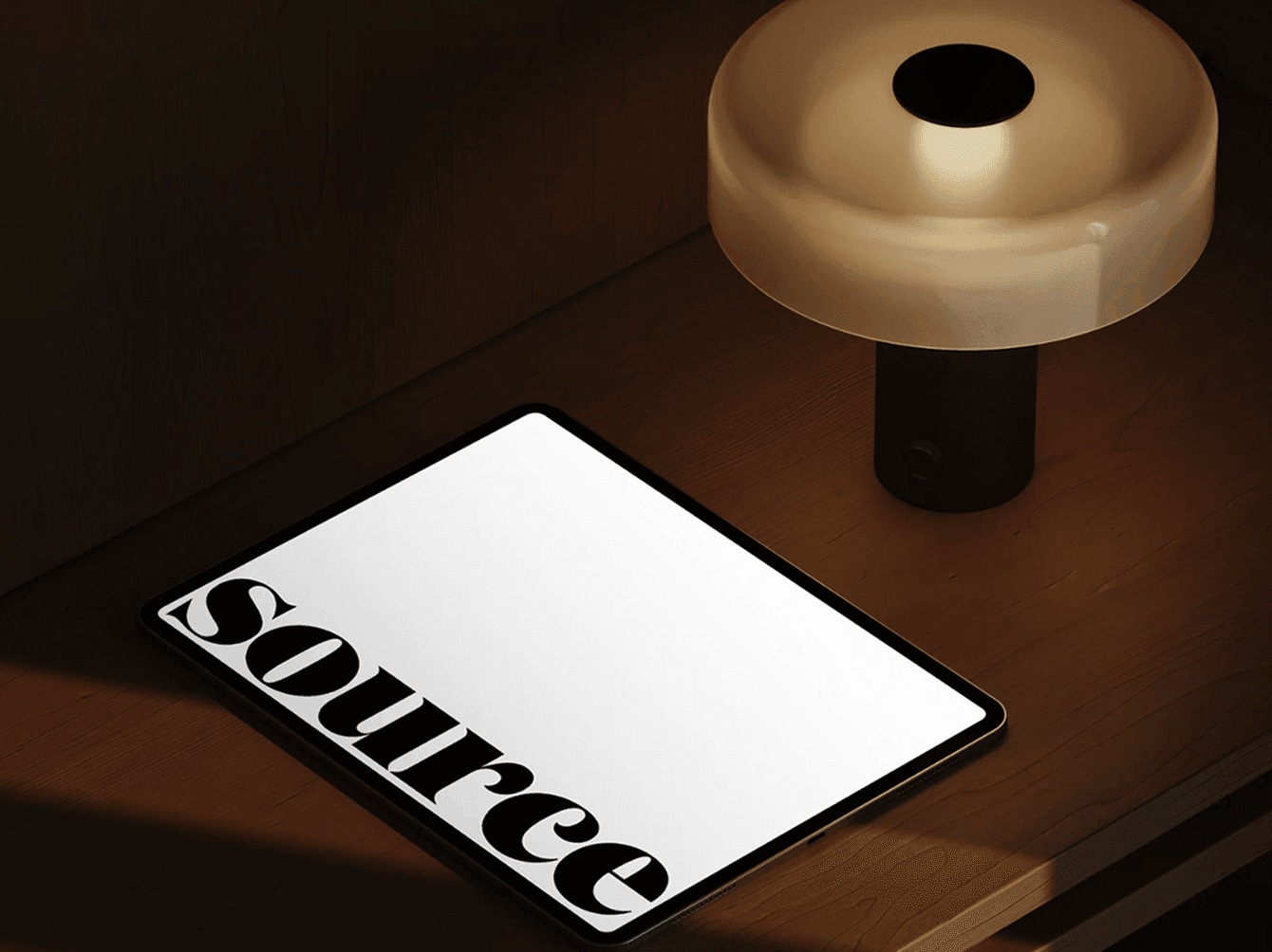 iPad mockup under warm lamp light on wooden table — cozy night scene.