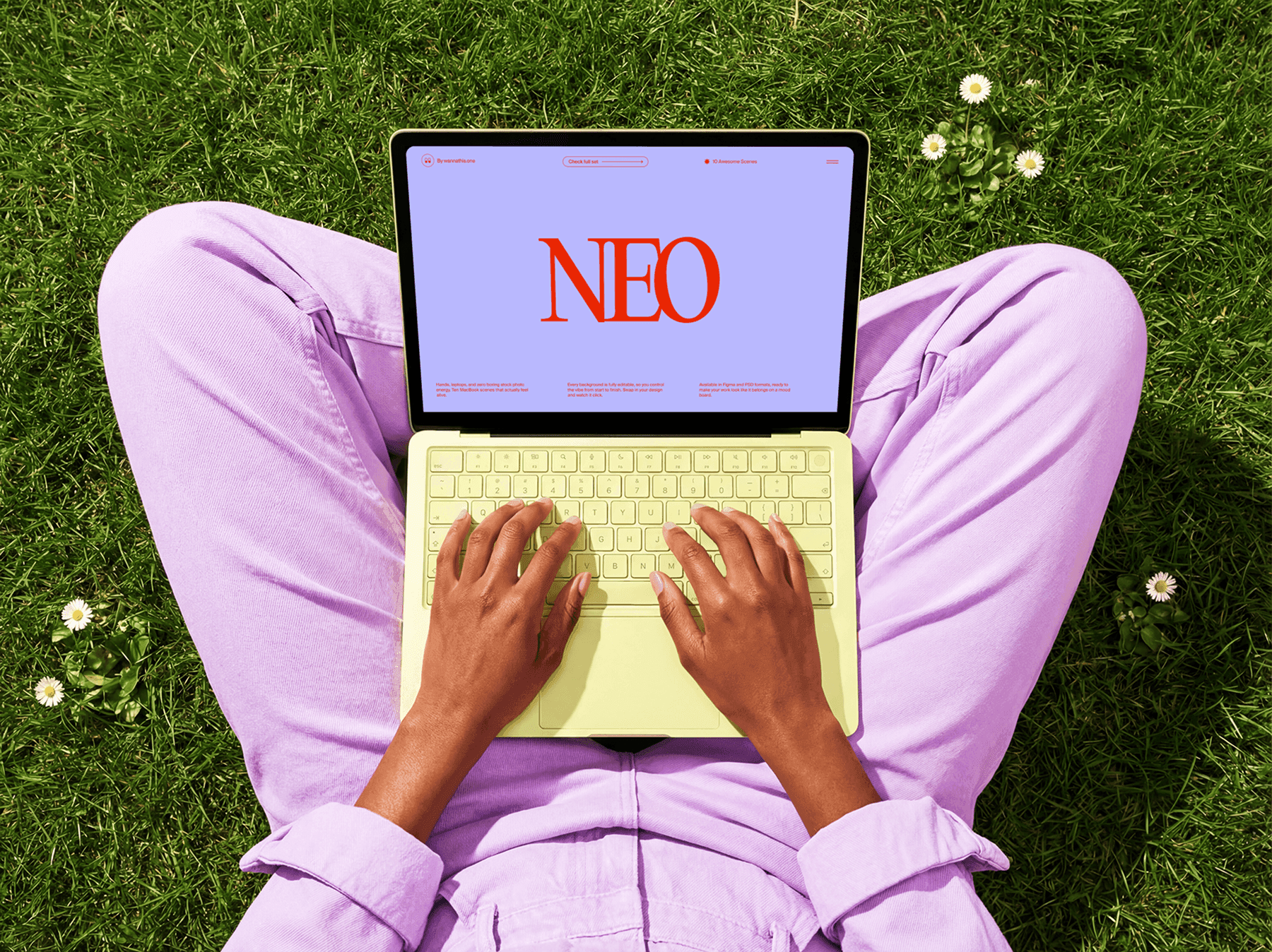 Person sitting on grass using a MacBook laptop from a top view