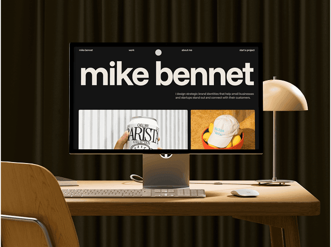 Mike Bennet Framer portfolio template on a Studio Display at a wooden desk, lowercase name hero with branding project cards, a template for identity designers