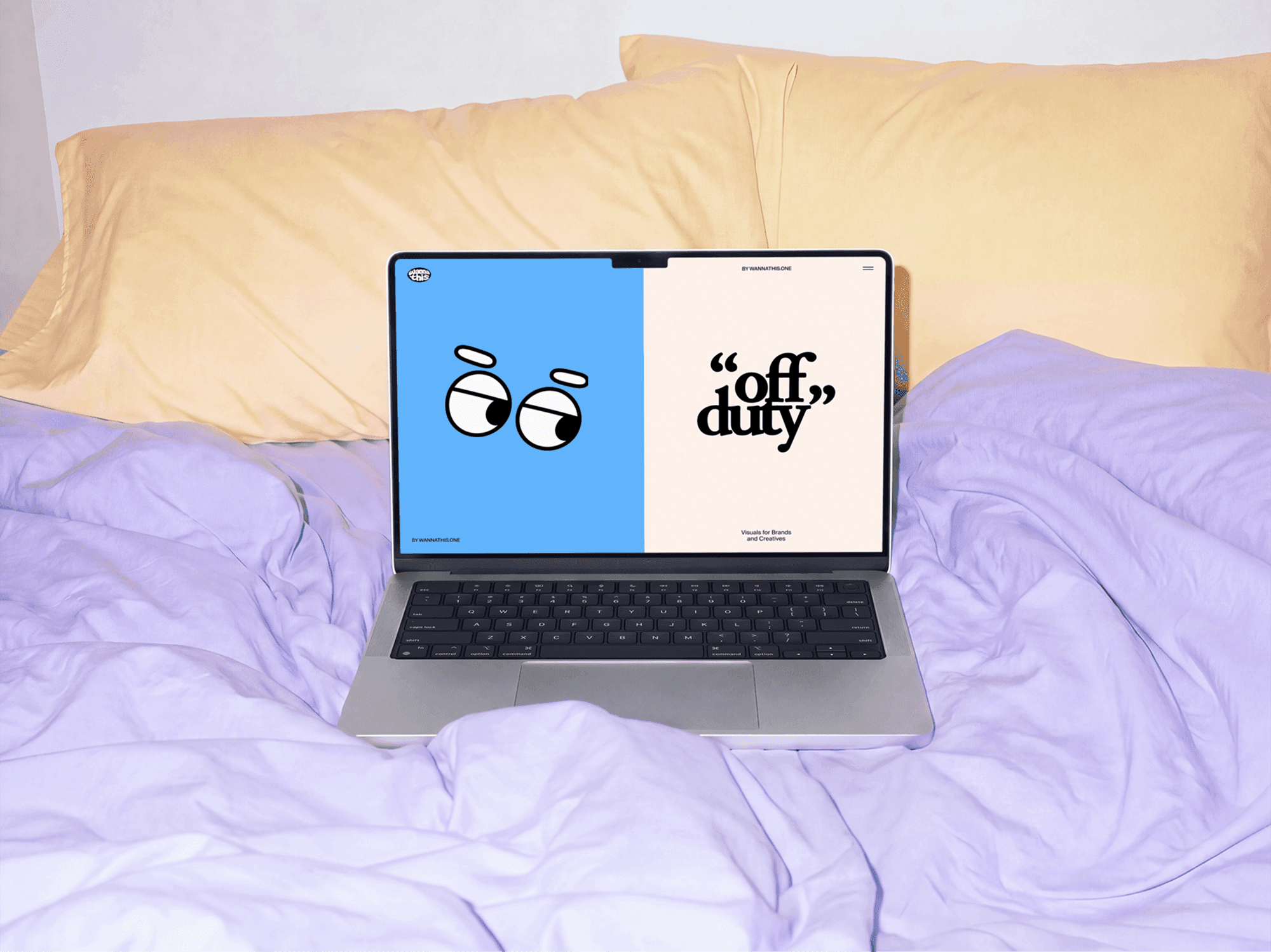 Open MacBook left on a bed with pillows stacked in the background