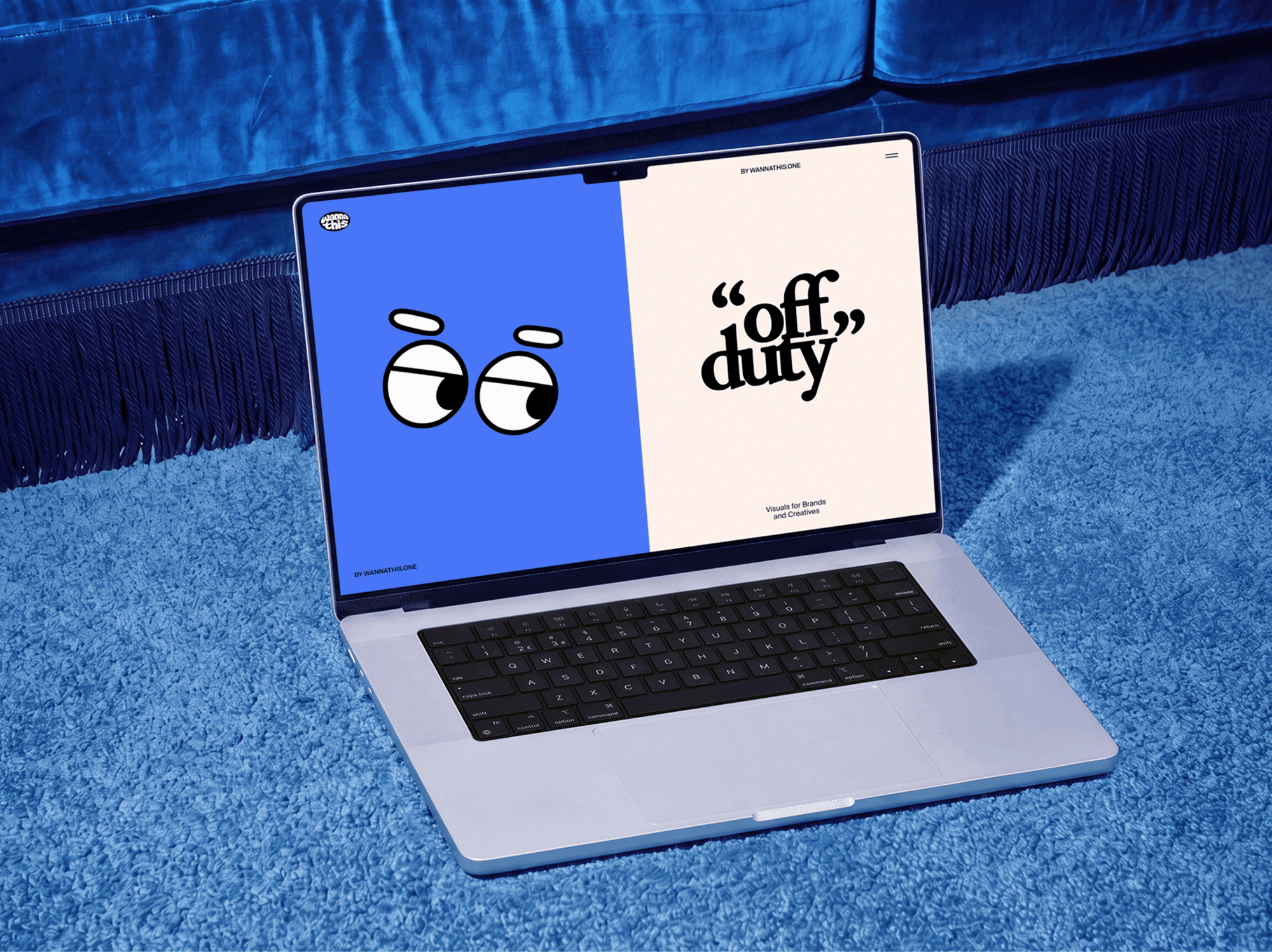 Open MacBook placed on a soft carpet directly in front of a low sofa