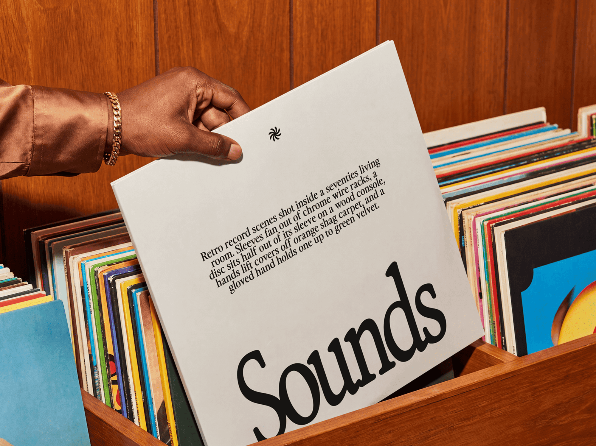 Hand lowering a vinyl record sleeve into a wooden crate packed with records