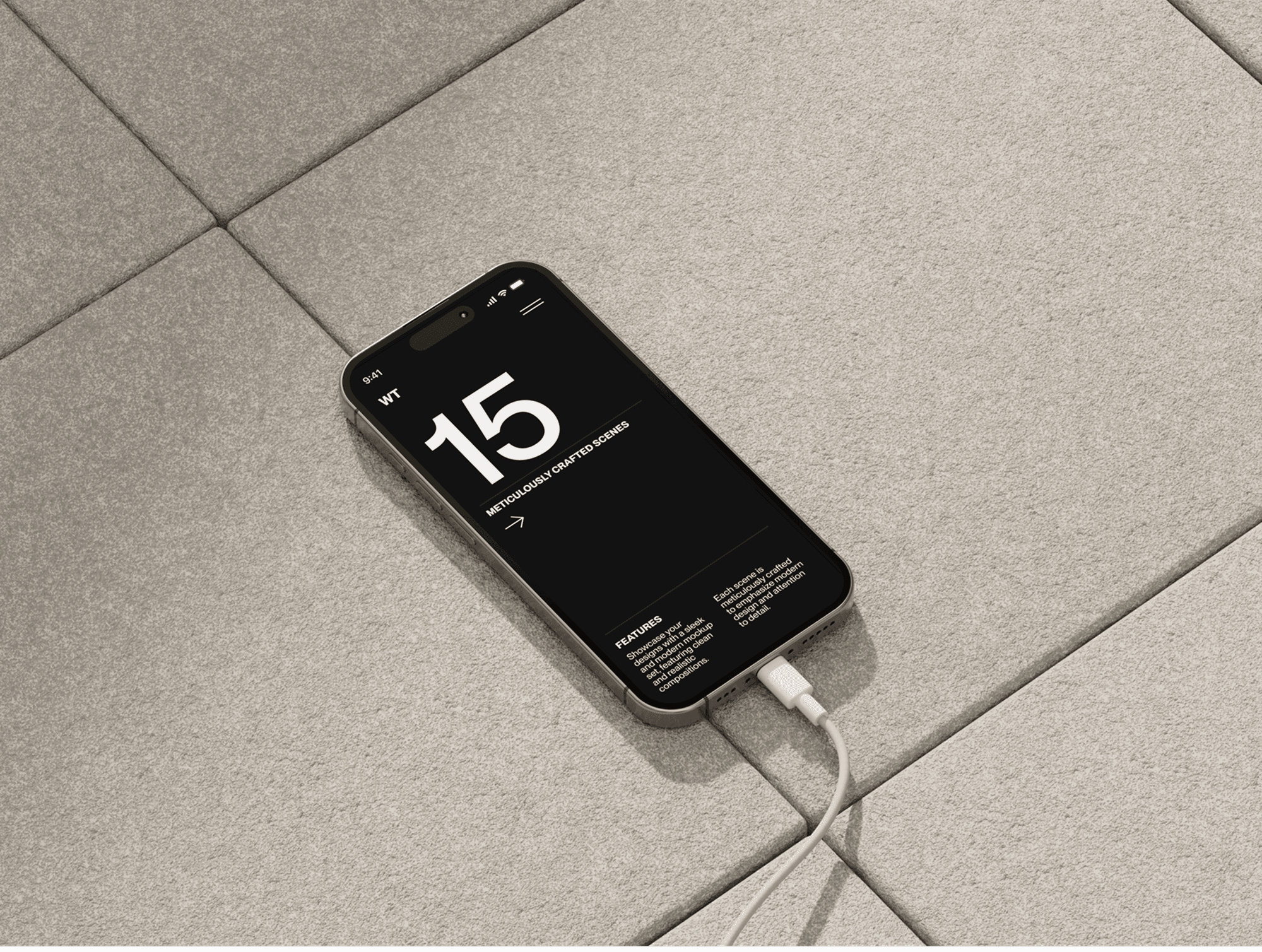 iPhone 16 mockup on a textured concrete tile floor with a charging cable.