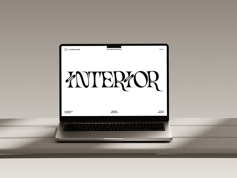 MacBook mockup placed at an angle on light-colored desk with soft grey wall