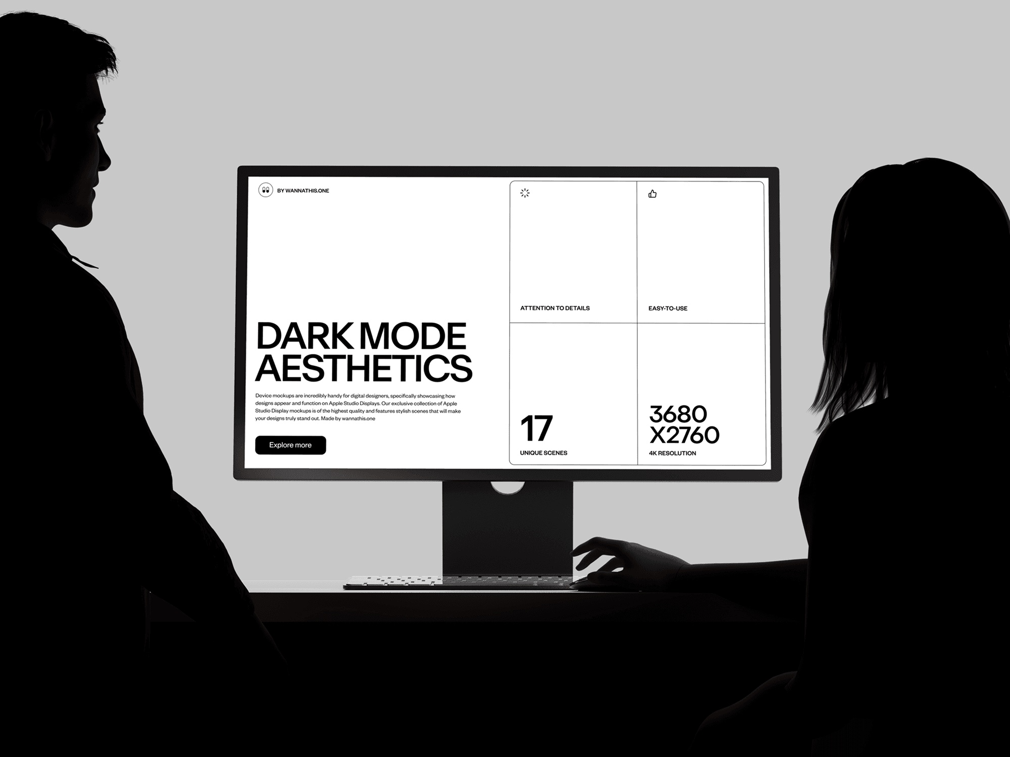 A silhouette of two people looking at a computer monitor mockup in a dark, high-contrast setting.