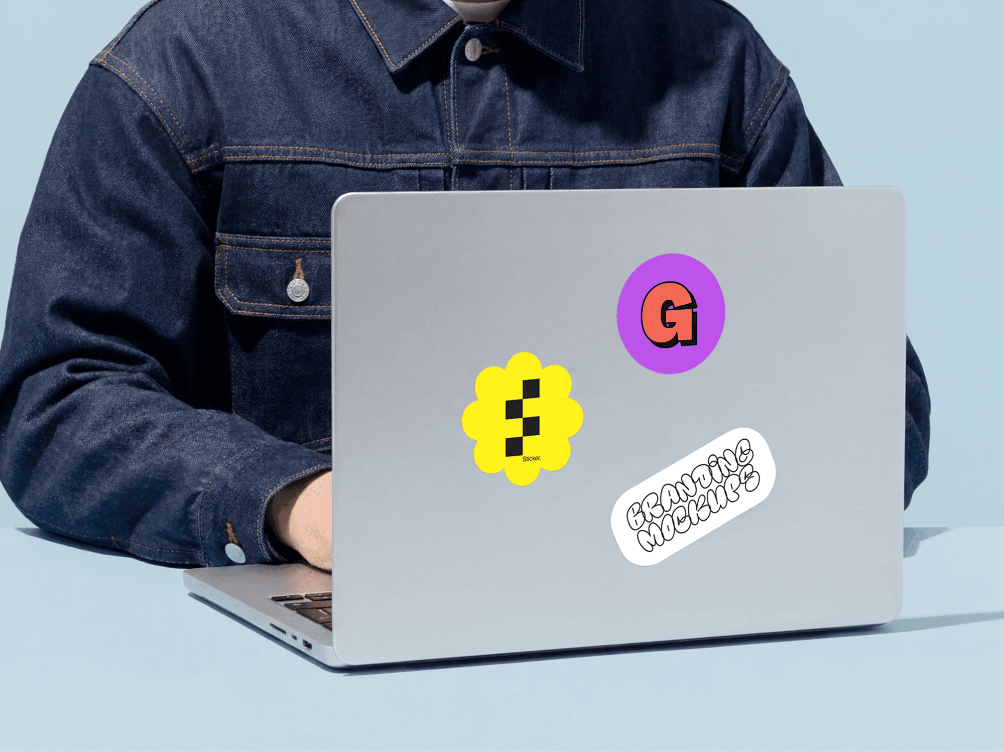 Multiple sticker mockups applied to the back of a laptop in a refined product studio scene