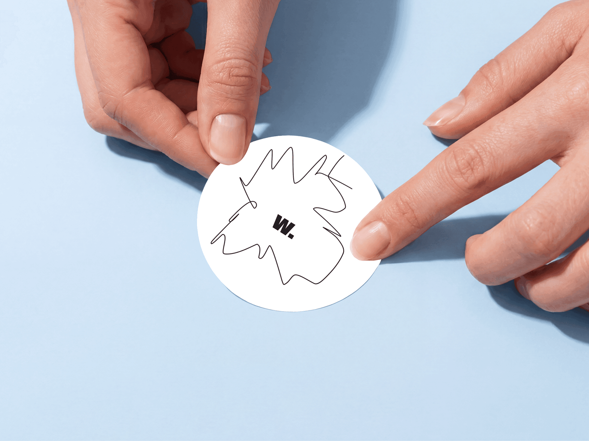 Hands applying a round sticker onto a smooth flat surface in a refined studio composition scene