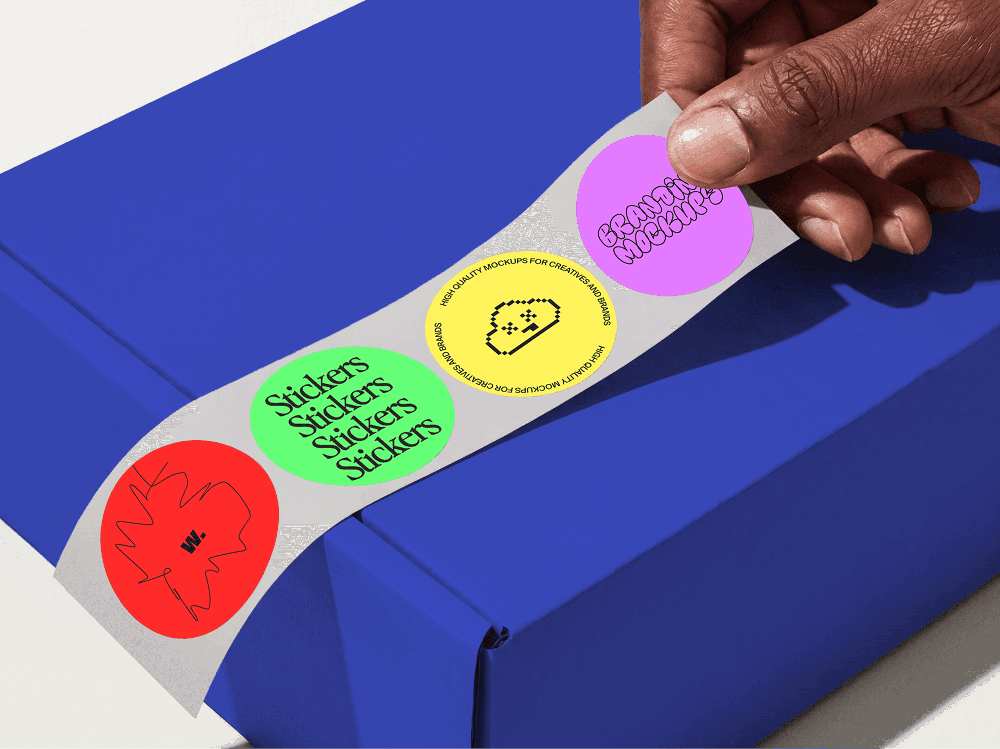 Person peeling stickers from a sticker sheet placed on top of a package in a refined studio scene