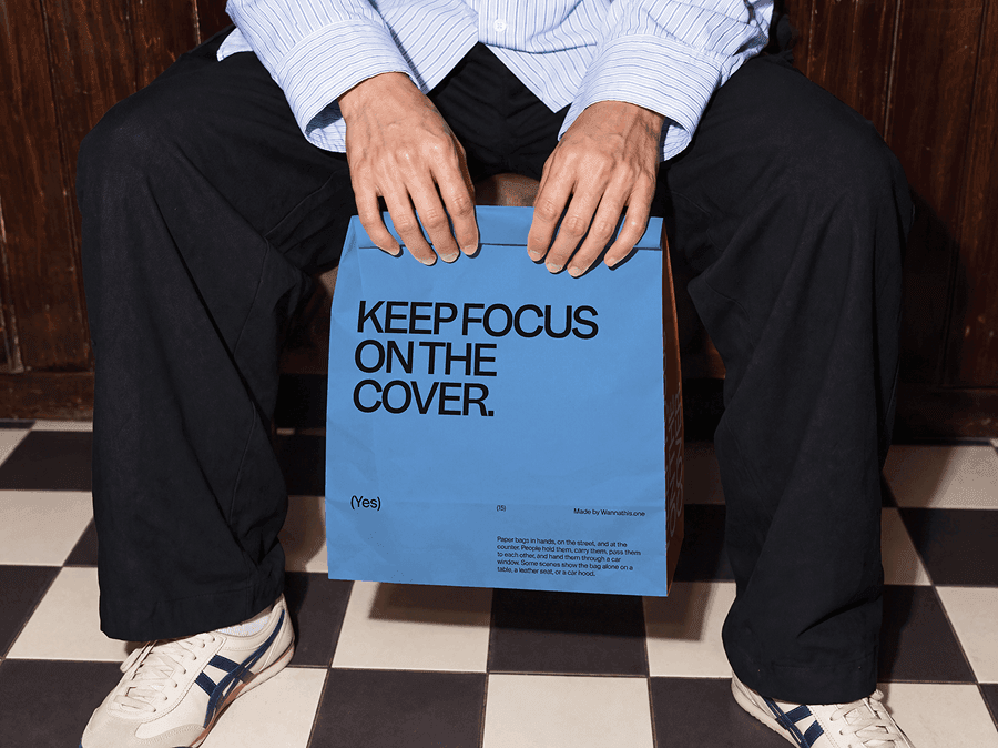 Paper shopping bag mockup resting between the knees of a person sitting down