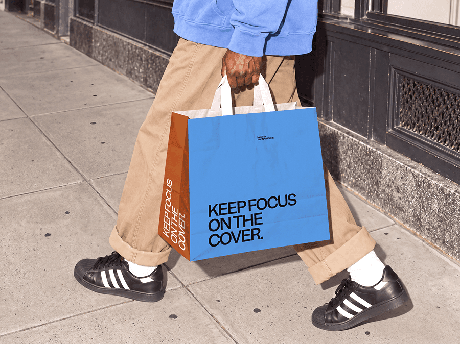 Paper shopping bag mockup with twisted handles carried along a city pavement