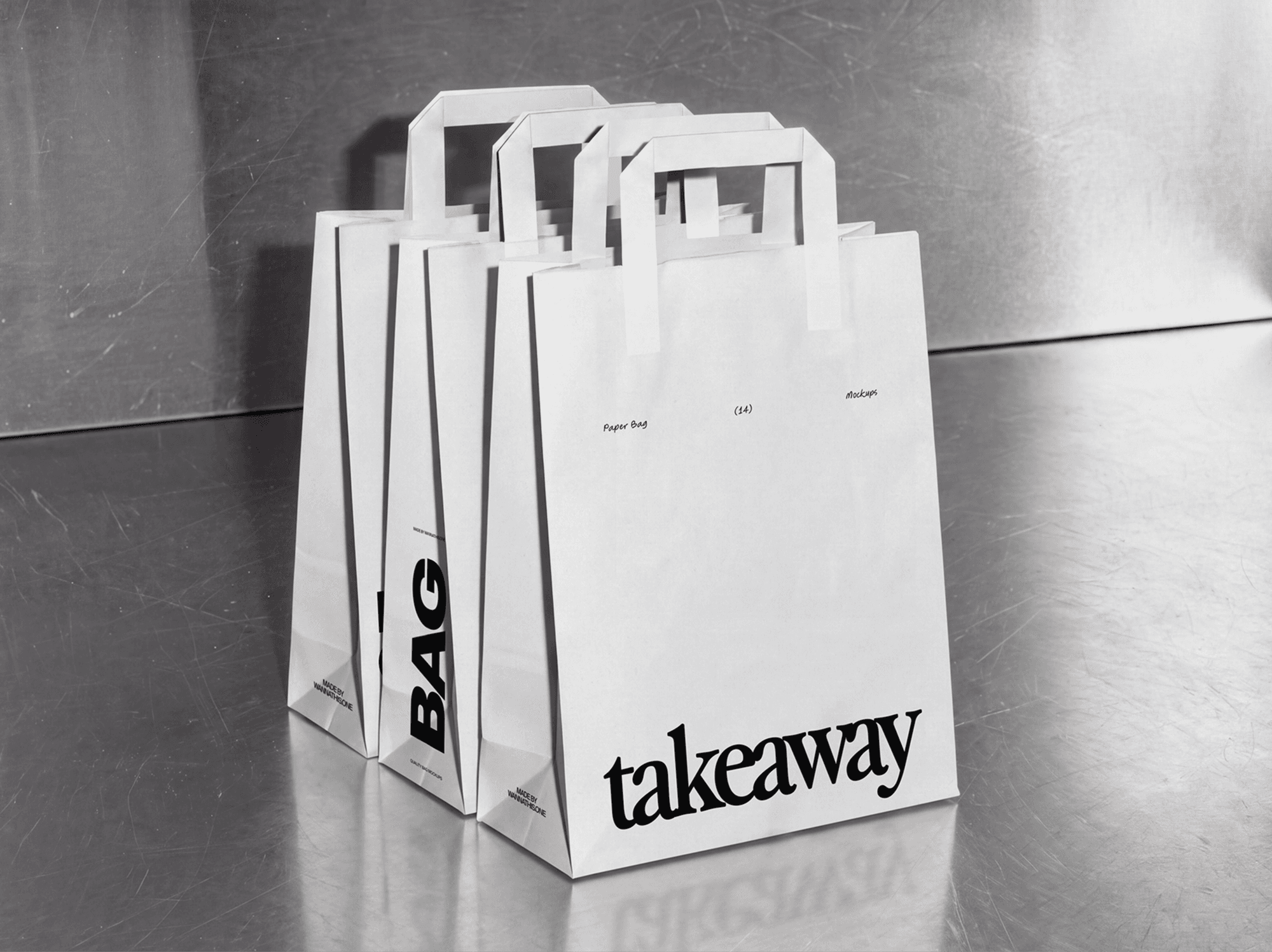 Several paper shopping bag mockups with handles lined up along a metal counter