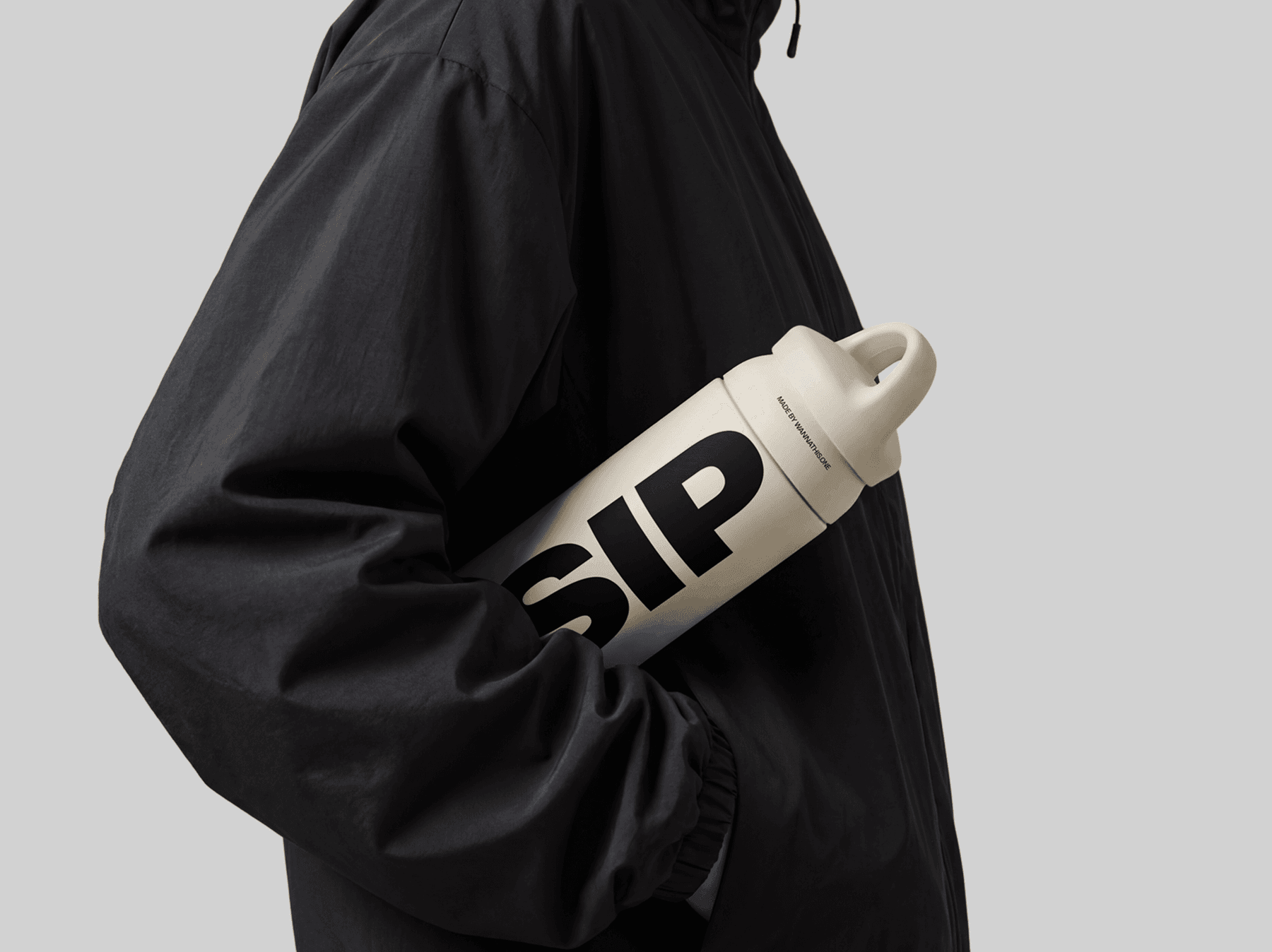 Travel bottle mockup carried under the arm of a person wearing a refined jacket in a casual lifestyle scene