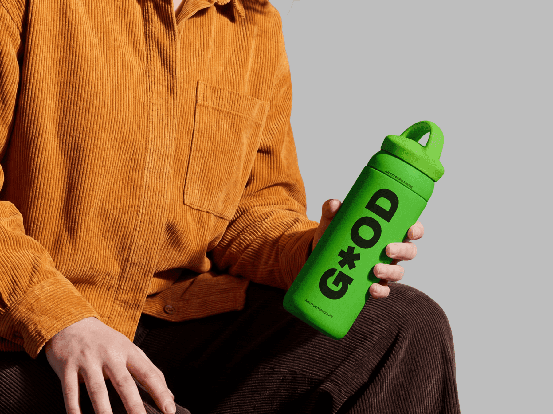 Travel bottle mockup held in a relaxed casual seated pose by a person in a refined lifestyle studio scene