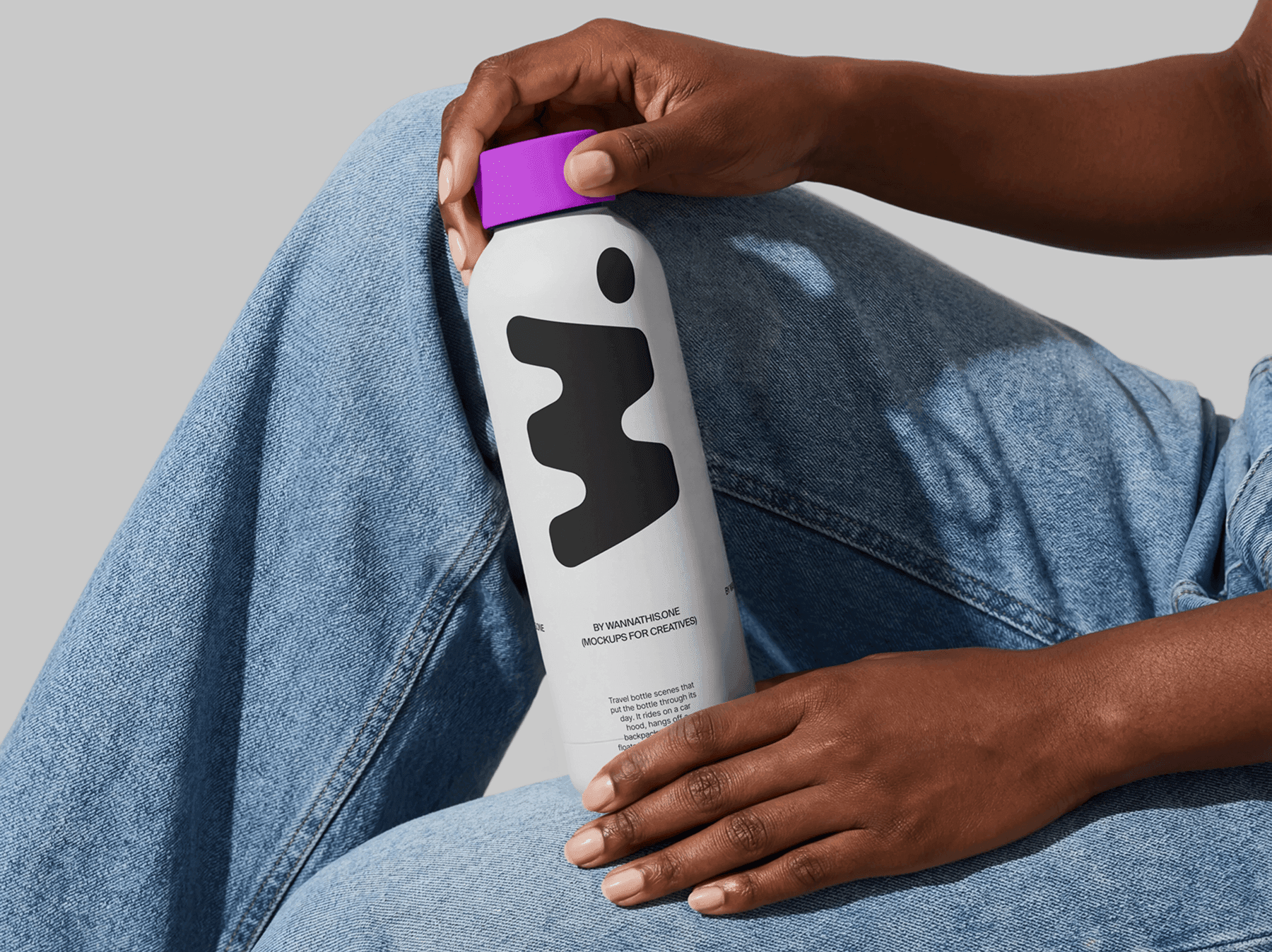Travel bottle mockup held in both hands by a seated person in a refined casual lifestyle scene